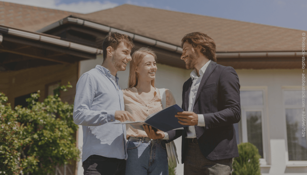 Ein Mann zeigt einem anderen Mann und einer Frau etwas in einer Mappe. Sie stehen vor einem Haus.